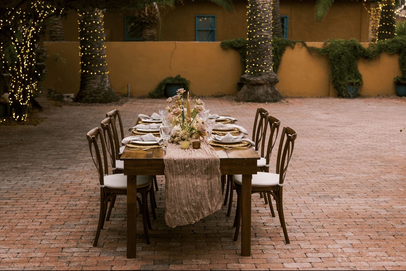 An outdoor courtyard set with a long banquet table for a wedding