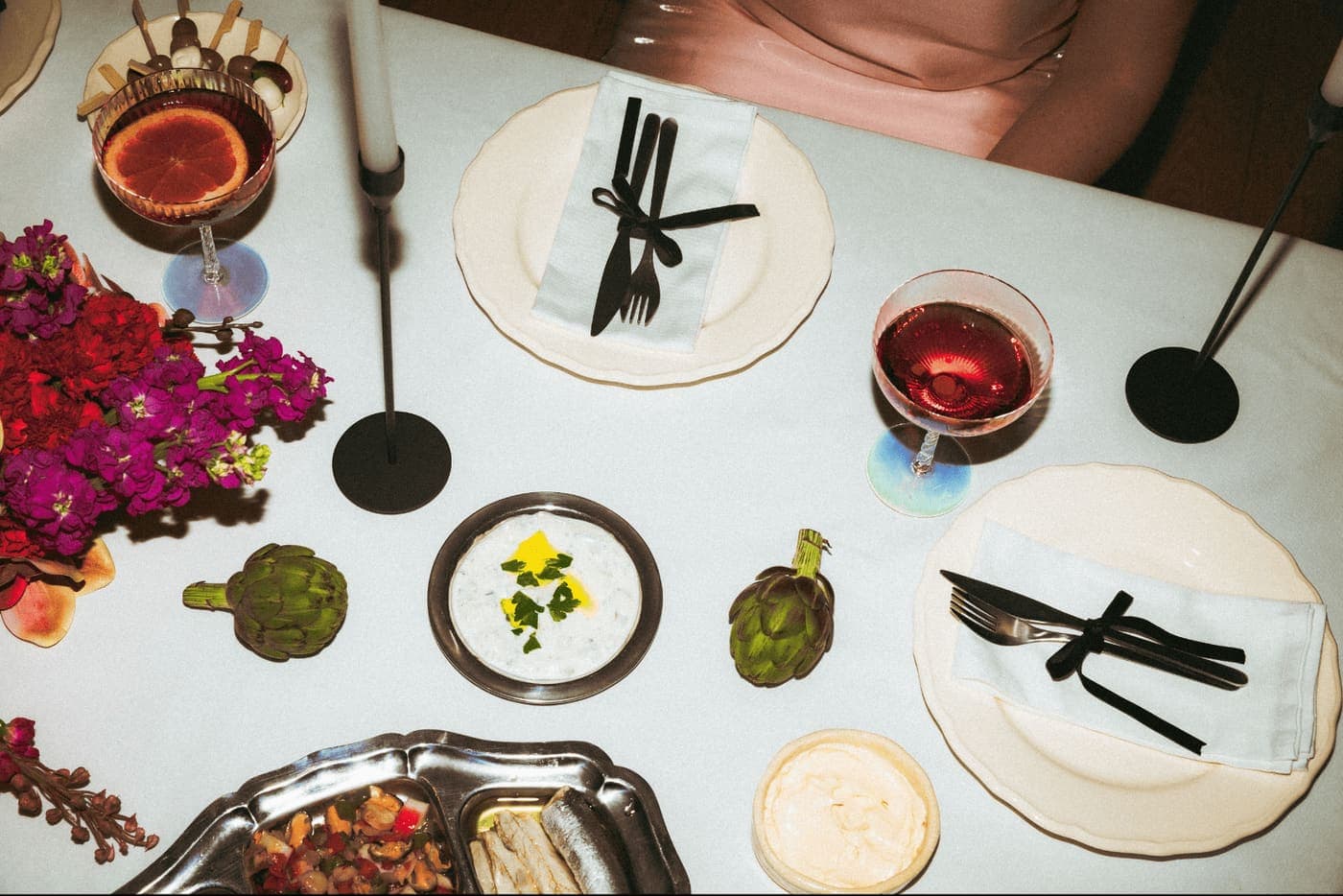 Overhead view of a wedding place setting with plated food and cocktails