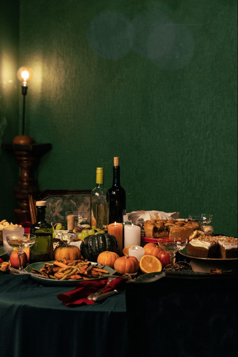 A rustic dinner table spread with wine, food, and candles
